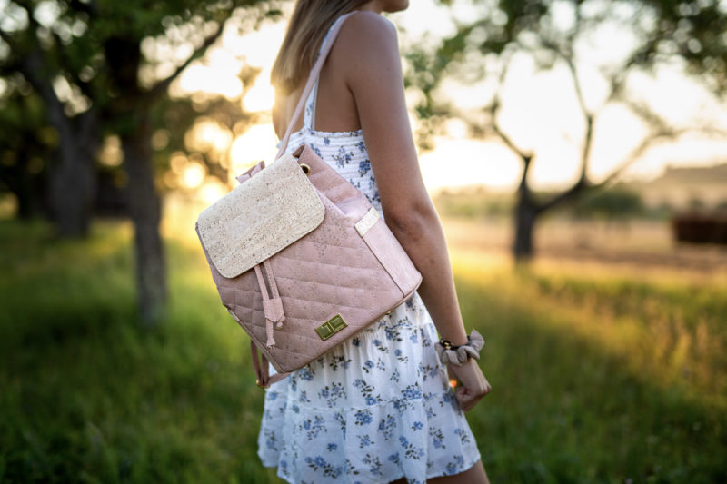 Sommer Frau läuft im Sommerkleid mit geschultertem Rucksack EMILIA aus Kork von Jorge Carmo beige Damenrucksack draußen bei Sonnenuntergang